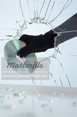 Main vol CD à travers une vitre cassée