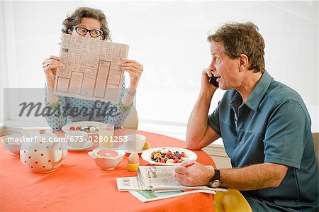 Couple having breakfast and checking newspaper classifieds