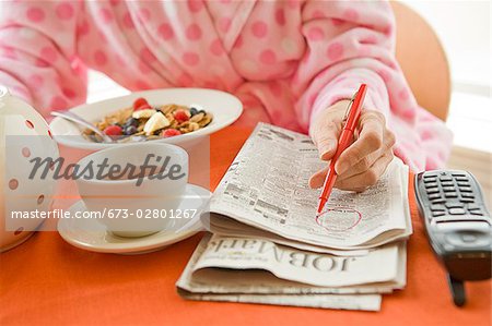 Woman having breakfast and researching classifieds