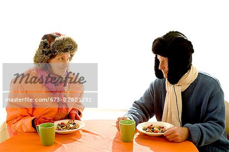 Couple dressed in winter apparel eating breakfast together