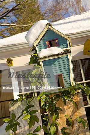 Bird house perched on a fence during winter