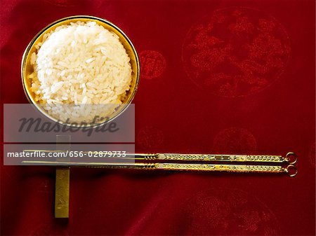 Goldener Reis-Schüssel mit Reis und Stäbchen