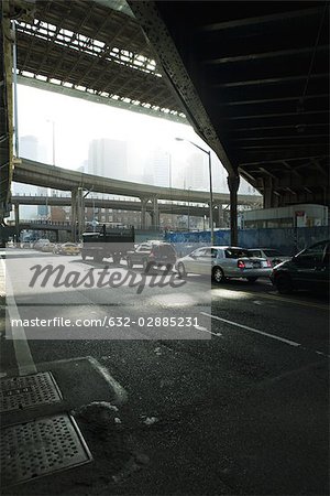 Traffic waiting at traffic signal on street beneath elevated road