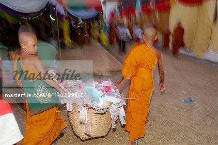 Deux jeunes moines transportant un panier de dons pendant le Festival de Luang Pha que pendant le carême bouddhique, à la grande pagode à Vientiane, au Laos, Indochine, Asie du sud-est, Asie
