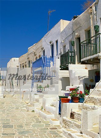 White houses with steps, balconies and flower pots line a street in The Kastro on Folegandros, Cyclades, Greek Islands, Greece, Europe