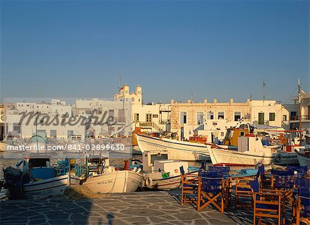 Tables and chairs on quayside, with boats in harbour in the town of Naousa on Paros, Cyclades, Greek Islands, Greece, Europe