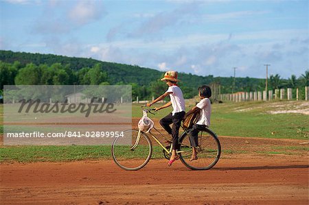 Two children riding on a bicycle through a rural area on Phu Quoc Island in south west Vietnam, Indochina, Southeast Asia, Asia