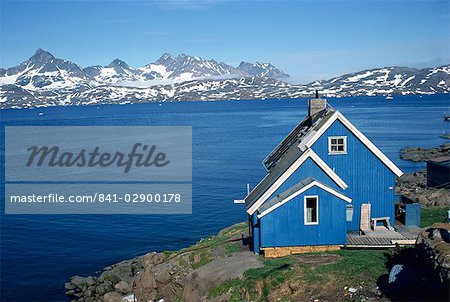 Maison en bois peint bleu sur la côte, avec les montagnes en arrière-plan, à Ammassalik, Groenland, les régions polaires