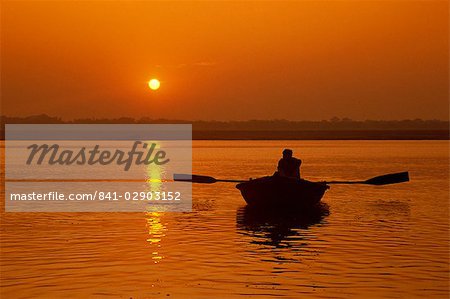 Figure in rowing boat silhouetted at sunset, River Ganges, Varanasi (Benares), Uttar Pradesh state, India, Asia