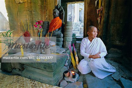 Buddhist nun meditating in the Bayon Temple, at Angkor, Siem Reap, Cambodia