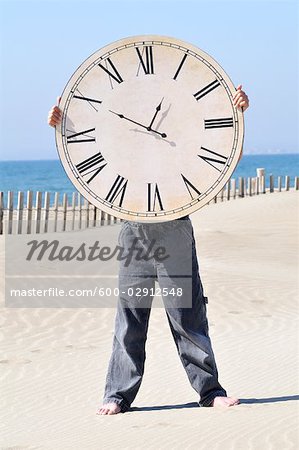 Boy Holding a Large Clock on the Beach