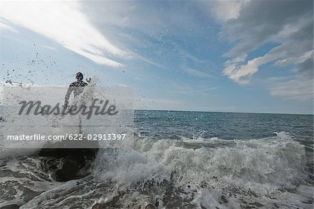 Young man in heavy waves of ocean with surfboard