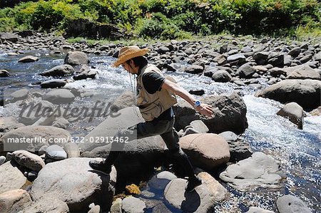 Man with straw hat walking on stones