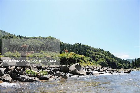 Man with straw hat standing on stone and fishing