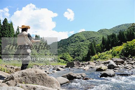 Man with straw hat standing and holding fishing rod