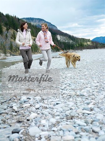 Two women jogging with dog at lake
