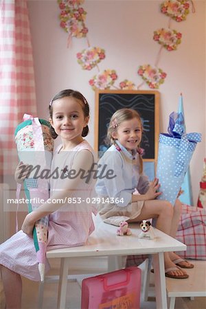 Two girls with cardboard cone sitting in table