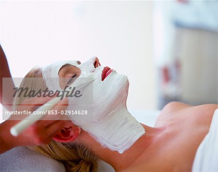 woman putting some creme on the face of another woman with a brush