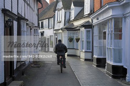 Homme cyclisme le long de la rue étroite, Alcester, Warwickshire, Midlands, Angleterre, Royaume-Uni, Europe