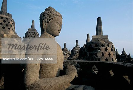 Buddha image sitting in open chamber with stupas in background, Borobudur Temple, UNESCO World Heritage Site, island of Java, Indonesia, Southeast Asia, Asia