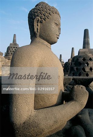 Seitenansicht einer Buddhastatue sitzend in offenen Kammer mit Stupas im Hintergrund, Borobudur Tempel, UNESCO Weltkulturerbe, Insel von Java, Indonesien, Südostasien, Asien