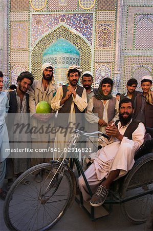 Handicapped man sitting in special modified bike surrounded by men outside Shrine of Hazrat Ali, Mazar-I-Sharif, Balkh province, Afghanistan, Asia