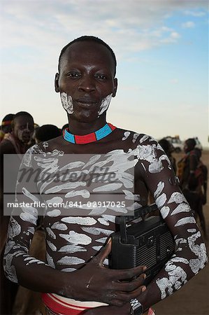 Karo man with body painted with animal pigments and clay, carrying radio under his arm, Kolcho village, Lower Omo Valley, Ethiopia, Africa