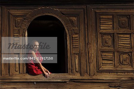 Novice monk sitting in window of 18th century wooden monastery of Nat Taung Kyaung (May-taung taik) thought to be the oldest wooden monastery in the area, Bagan (Pagan), Myanmar (Burma), Asia