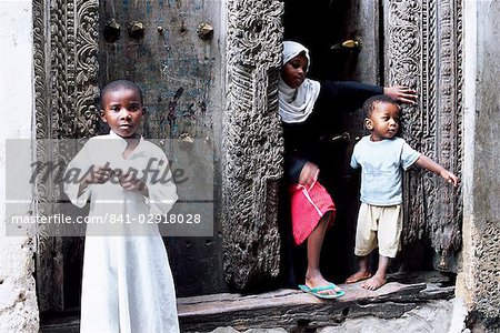 Jeunes enfants musulmans devant une porte sculptée ornée, Stone Town, Zanzibar, Tanzanie, Afrique