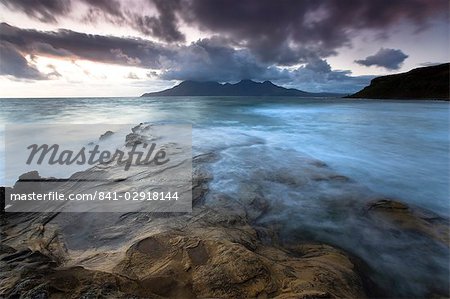 Regardant vers l'île de Rum crépuscule des roches à sables chantants (Camas Sgiotaig), île de Eigg, Hébrides intérieures en Écosse, Royaume-Uni, Europe