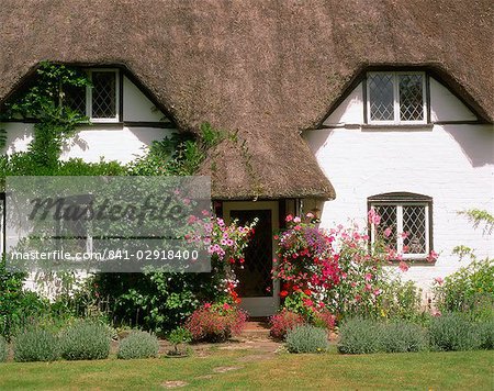 Thatched cottage with hanging baskets full of summer flowers in Dorset, England, United Kingdom, Europe