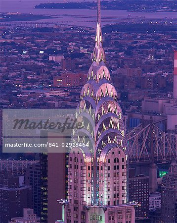 The top of the Chrysler Building illuminated in the evening with a bridge and the city of New York in the background, United States of America, North America