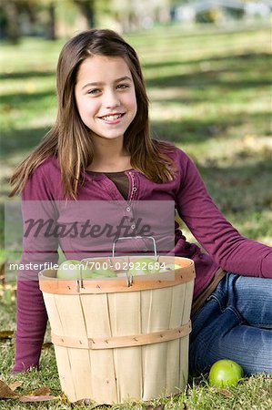 Mädchen sitzen durch einen Korb mit Äpfeln