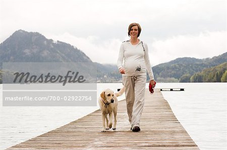 Femme enceinte marchant sur le quai avec son chien