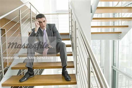 Businessman on office staircase holding his head