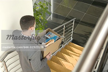 Businessman on office staircase with box of belongings