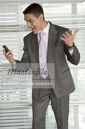 Businessman in office shouting at cell phone