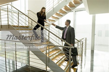 Femme d'affaires et homme d'affaires d'échanger des documents sur l'escalier de bureau