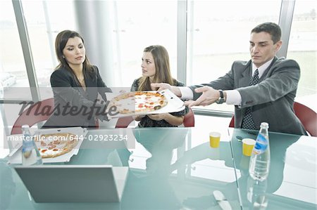 Business people sharing pizza at desk