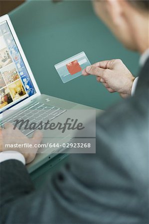 Businessman holding credit card at laptop