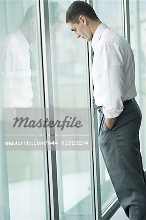 Homme d'affaires, regardant par la fenêtre, main dans la poche