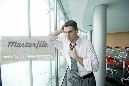 Businessman looking out the window, adjusting tie