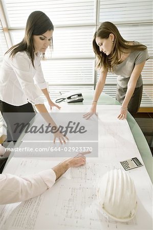 Professionnels à la recherche de plans architecturaux sur le bureau