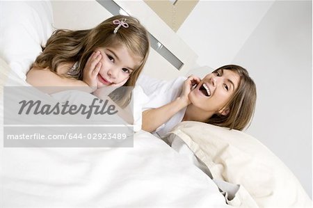 Junge Frau und Mädchen auf dem Bett lächelnd