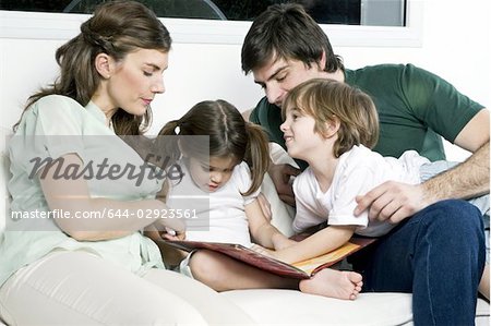 Junges Paar auf Couch mit Kindern lesen