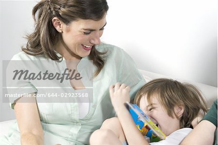Jeune femme sur le canapé avec le garçon lire