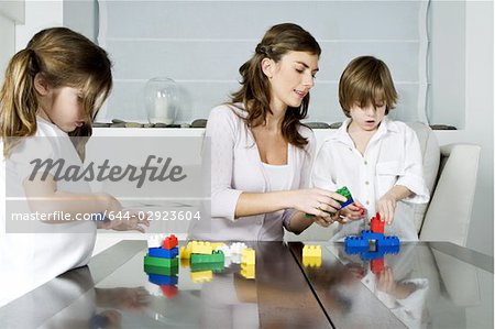 Young woman and boy and girl playing with building blocks