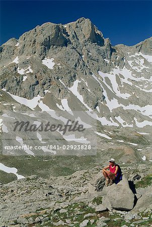 Trekker resting on a rock in the high mountains of the central massif of the Picos de Europa in Cantabria, Spain, Europe