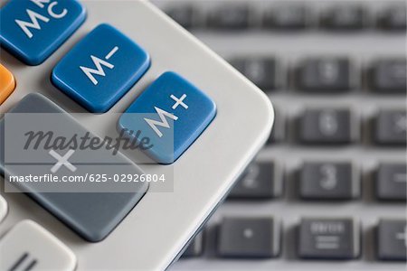 Mathematical symbols on a calculator and a computer keyboard in the background