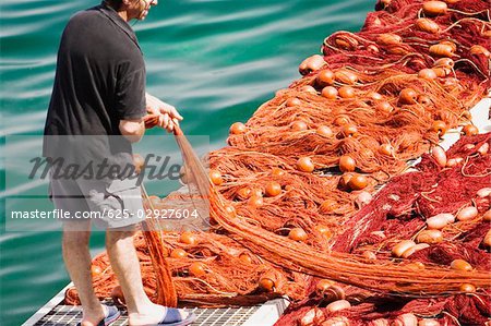 Rear view of a fisherman holding a commercial fishing net, Marina Grande, Capri, Sorrento, Sorrentine Peninsula, Naples Province, Campania, Italy